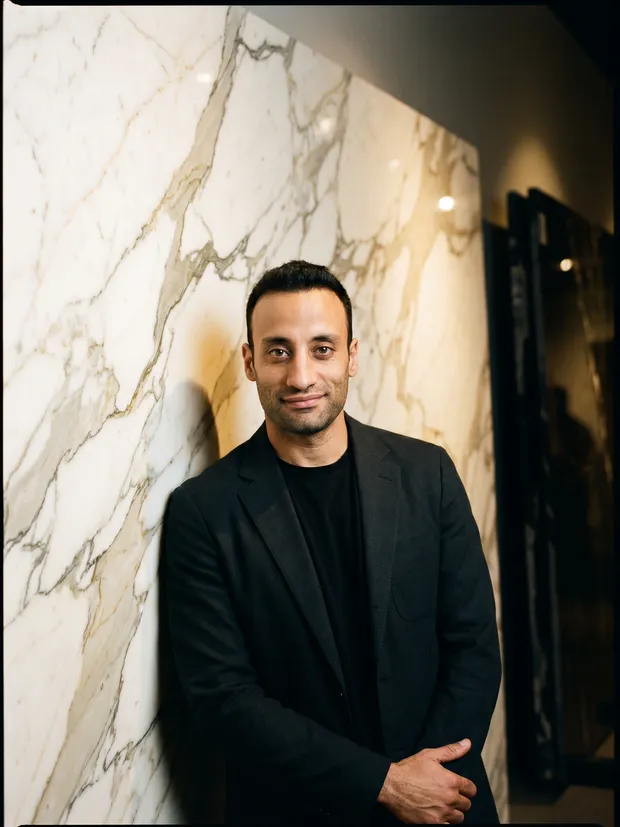 Burak Sakar leaning against a Calacatta marble slab in the showroom